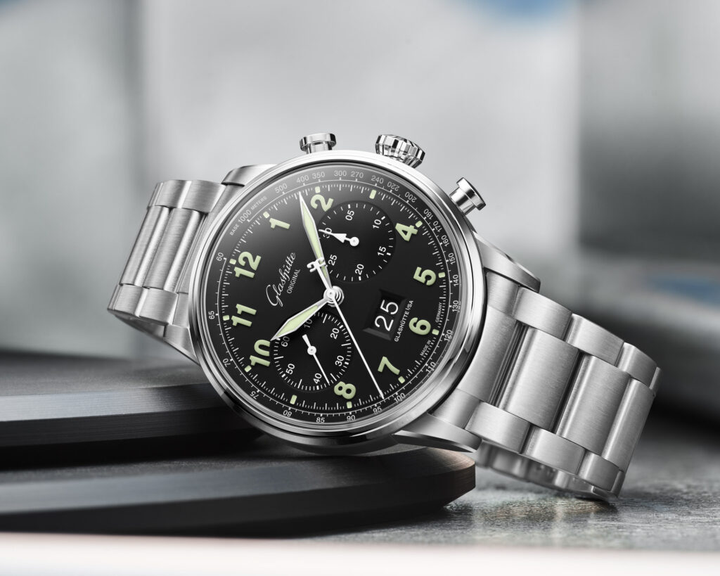 Two Glashuette Original Senator Chronograph watches side by side: the classic silver-grain model on the left and the black-lacquer Navigator pilot variant on the right, both in stainless steel